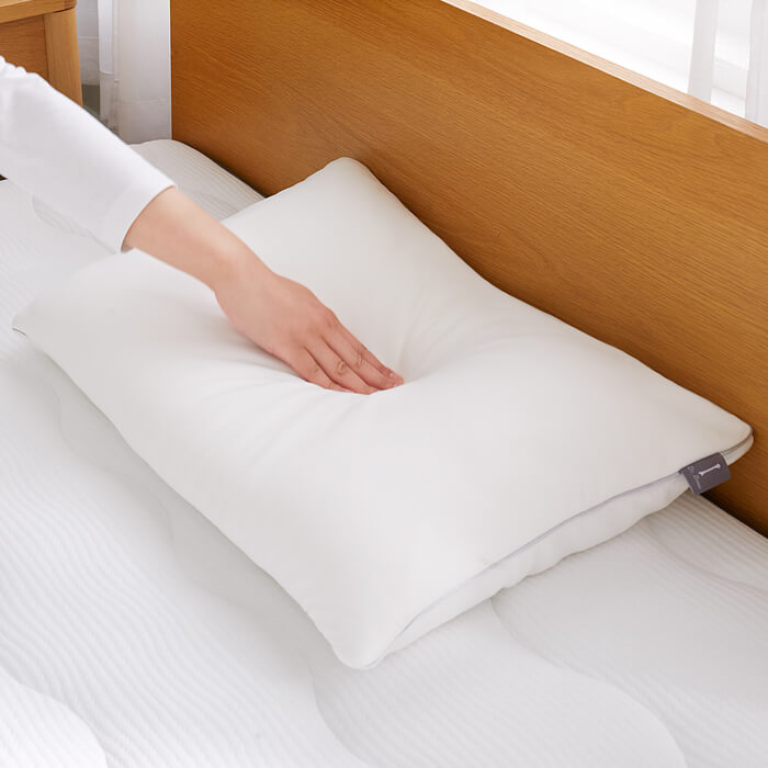 Dr.Bones Pillow for kumonoyasuragiを手で押しているシーン（やわらかさのイメージ）